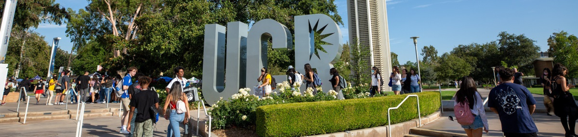 Students walking past UCR sign and bell tower