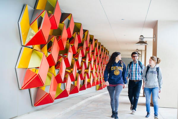 Students walking past genomics building art installation