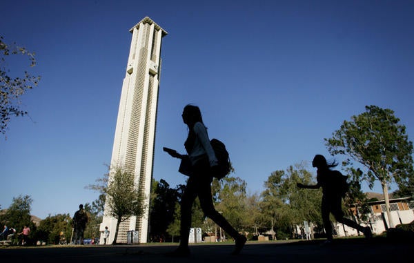 Student walking on UCR campus, bell tower in the background (c) UCR / Stan Lim