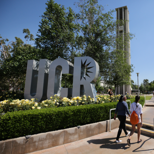 Students walking past UCR sign and belltower