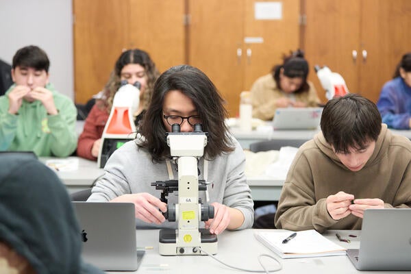 Student looking through microscope in a lab.