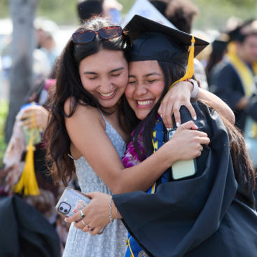 UCR graduates hugging at commencement ceremony