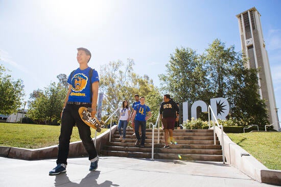 UC Riverside students walking by UCR sign and clocktower