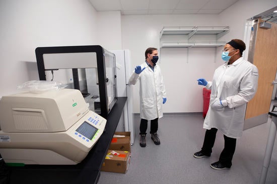 Matthew Collin, genomics core manager, left, and assistant professor Juliet Morrison set up the COVID-19 testing laboratory