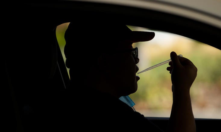Zhaojie Meng, a staff member with Biomedical Sciences, is silhouetted as he collects his saliva for a COVID-19 test from his car on Wednesday, September 9, 2020.(UCR/Stan Lim)